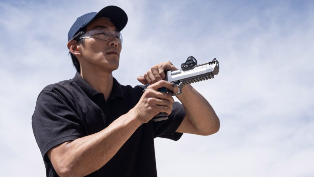 Man racking pistol slide outdoors. Photo by Hi-Lux