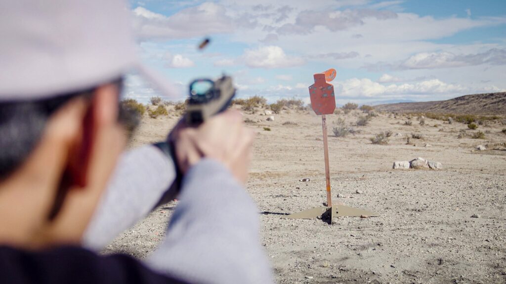 Man holding pistol with target in distance. Photo by Hi-Lux