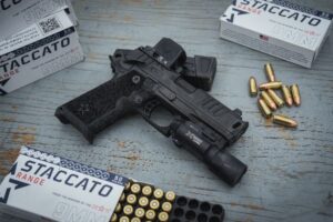 staccato with optic lying on table surrounded by ammunition